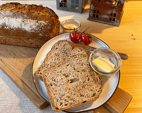 fertig gebackenes Mehrkorn-Quarkbrot, zwei Scheiben liegen auf einem Teller aufgeschnitten