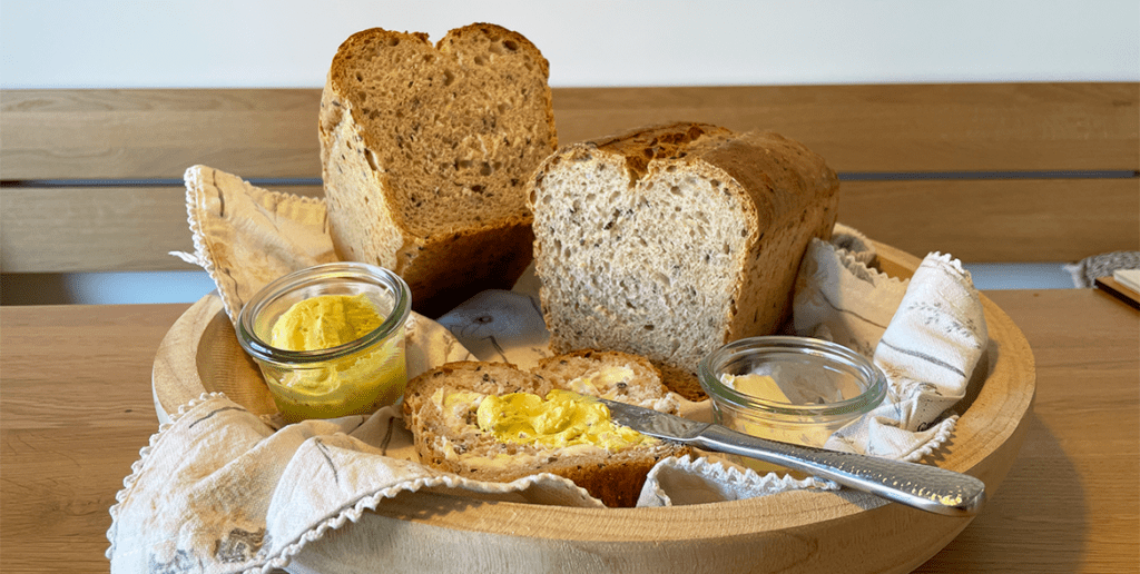 fertig gebackenes Urkorn-Joghurtbrot aufgeschnitten mit Butter und Dattel-Curry-Dip beschmiert