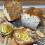fertig gebackenes Urkorn-Joghurtbrot aufgeschnitten mit Butter und Dattel-Curry-Dip beschmiert