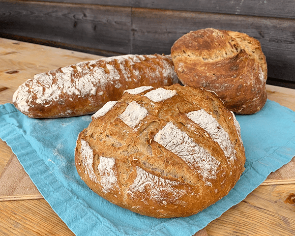 drei verschieden geformte Brotlaibe liegen auf einem blauen Tuch